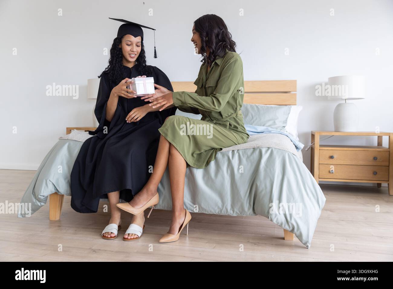 Diverse mom and teenage daughter wearing graduation gown and dress sitting on bed Stock Photo - Alamy Diverse mom and teenage daughter wearing graduation gown and dress sitting on bed Stock Photo - Alamy