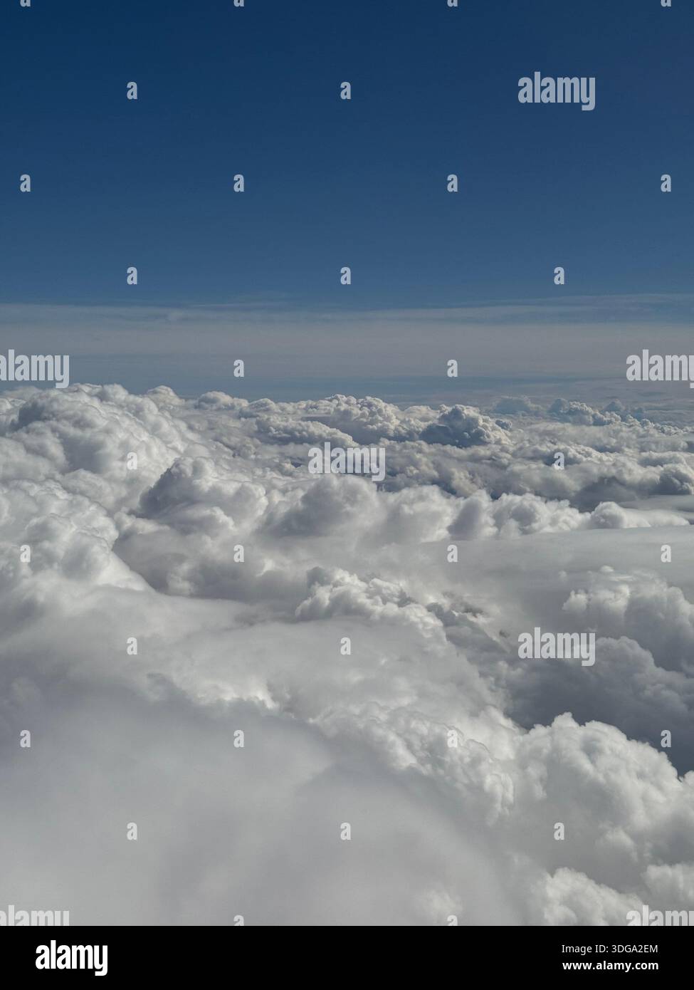 Aerial view above the clouds showing a vast cloudscape under a deep blue sky, creating a calm and minimal natural background. - Smartphone Captured Stock Image