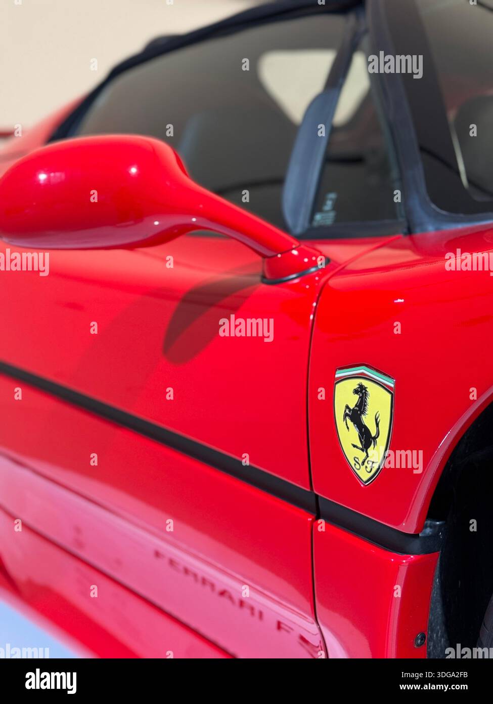 Close-up detail of a red Ferrari sports car with the iconic prancing horse badge on display at the Ferrari Museum in Modena, Italy - Smartphone Captured Stock Image