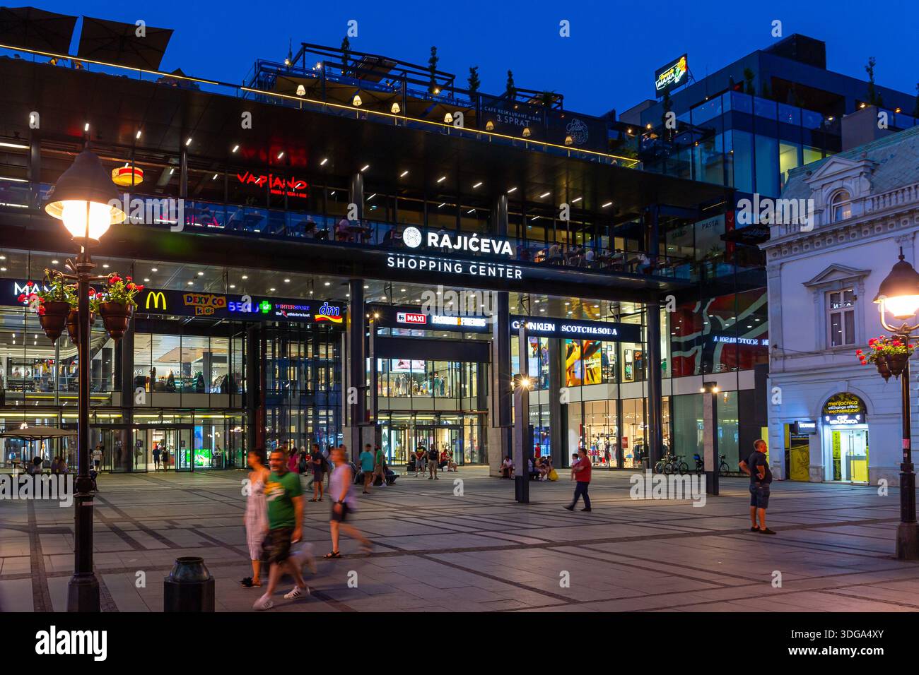 Belgrade, Serbia, 13.06.22. Rajiceva Shopping Center in Belgrade, Serbia, night view with illuminated exterior facade of the shopping mall with people Stock Photo