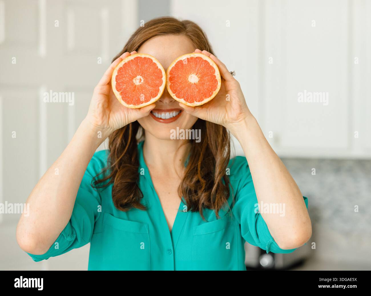 Beautiful Woman Holding Ruby Red Grapefruit Cut in Half Stock Photo
