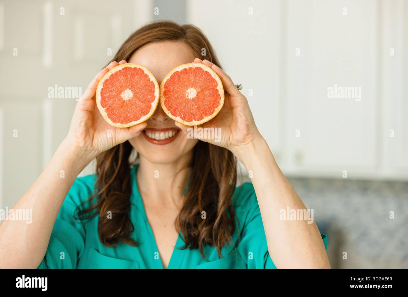 Beautiful Woman Holding Ruby Red Grapefruit Cut in Half Stock Photo