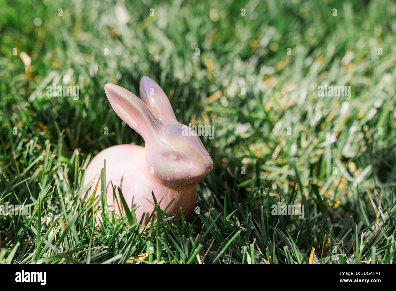 Pink ceramic Easter bunny in the grass. Stock Photo