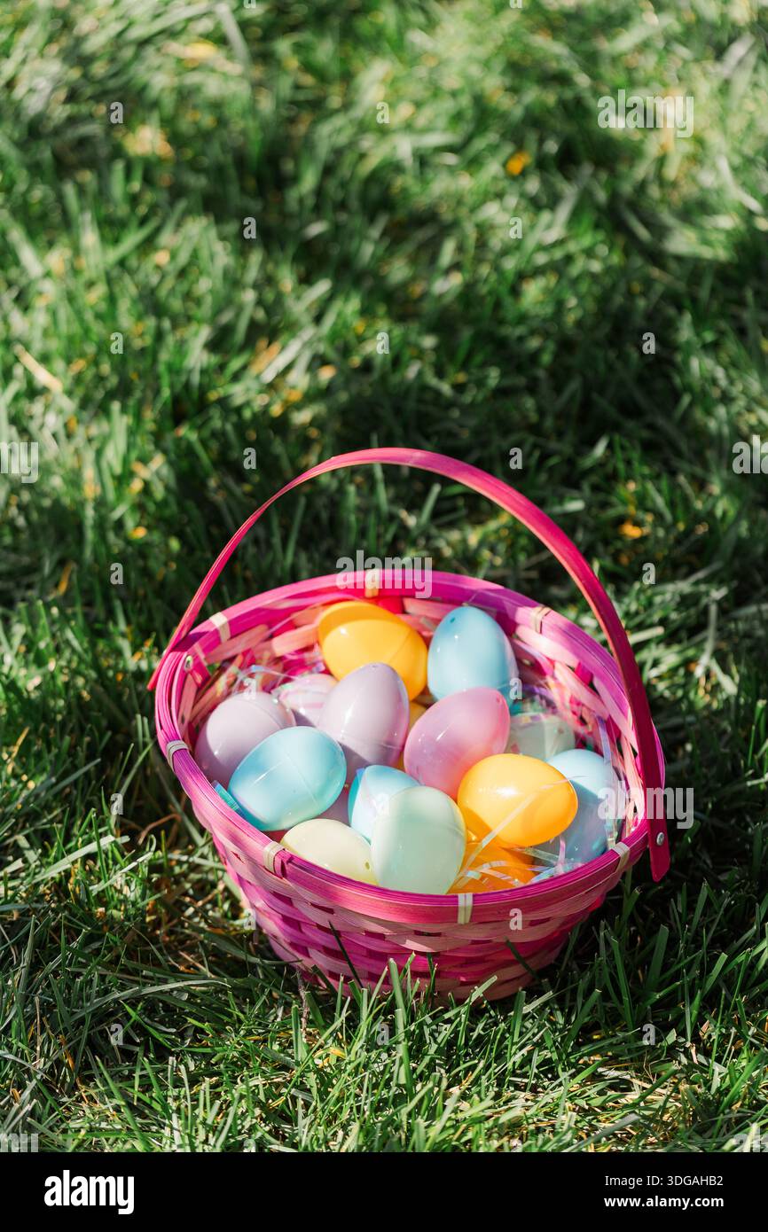 Pink Easter basket filled with eggs sitting in grass. Stock Photo
