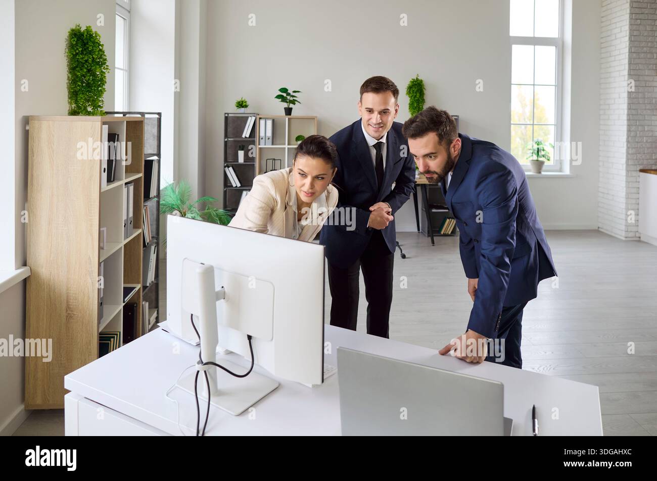 Corporate team discussing strategy at computer in bright office, analyzing data Stock Photo