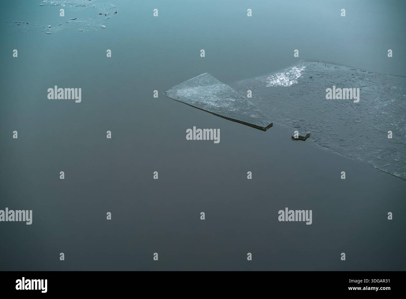 Broken Ice Sheets Floating on Calm Water Surface in Winter Stock Photo