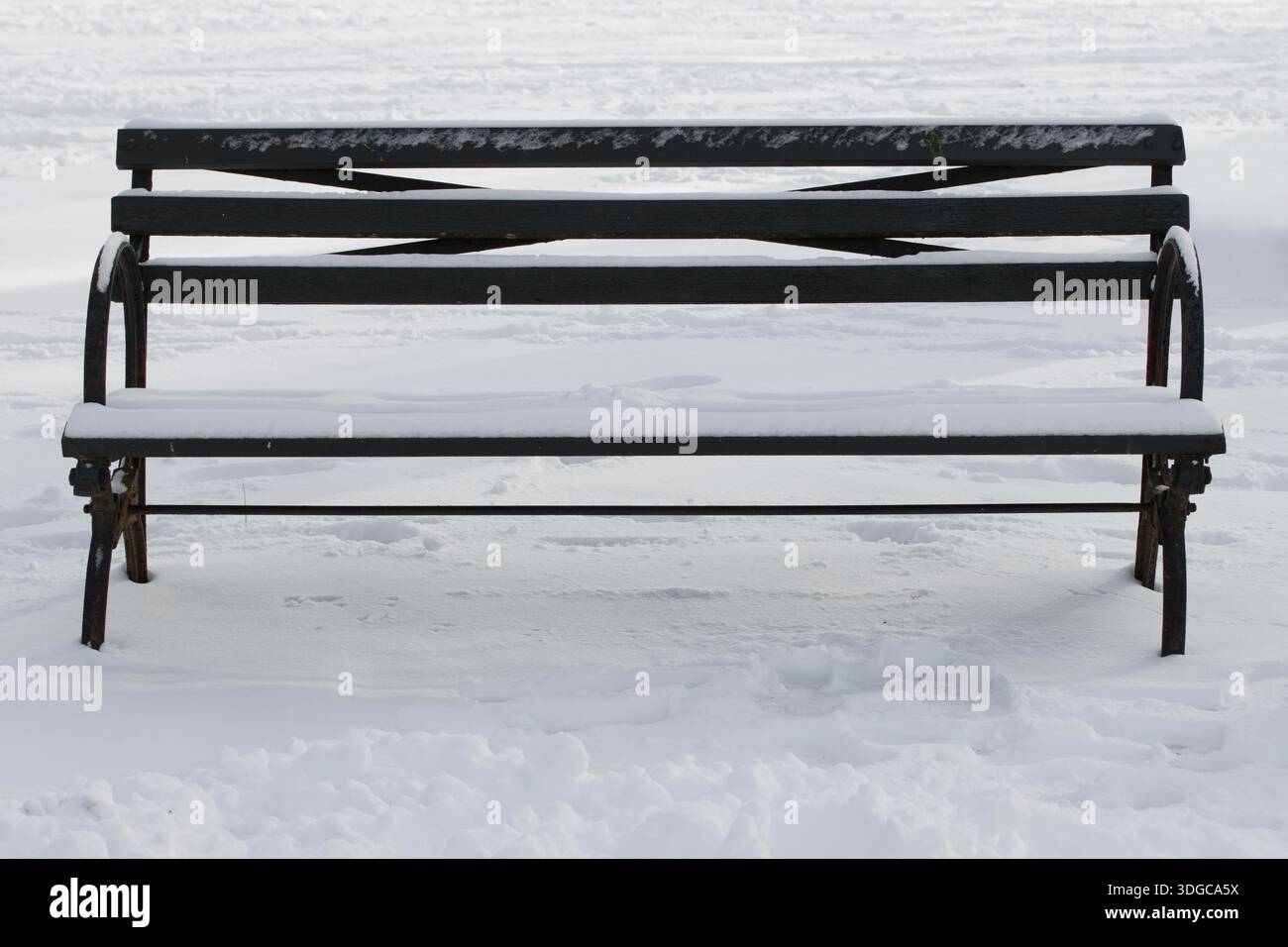 empty park bench covered in pure white snow, surrounded by snow on the ground, copy space Stock Photo