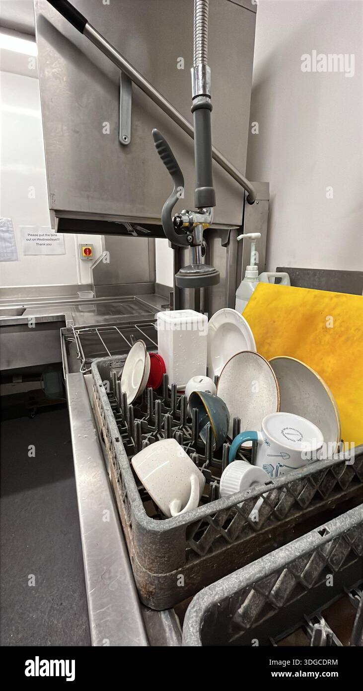 Commercial kitchen with pass-through dishwasher and pre-rinse spray faucet for hygienic dishwashing. - Smartphone Captured Stock Image