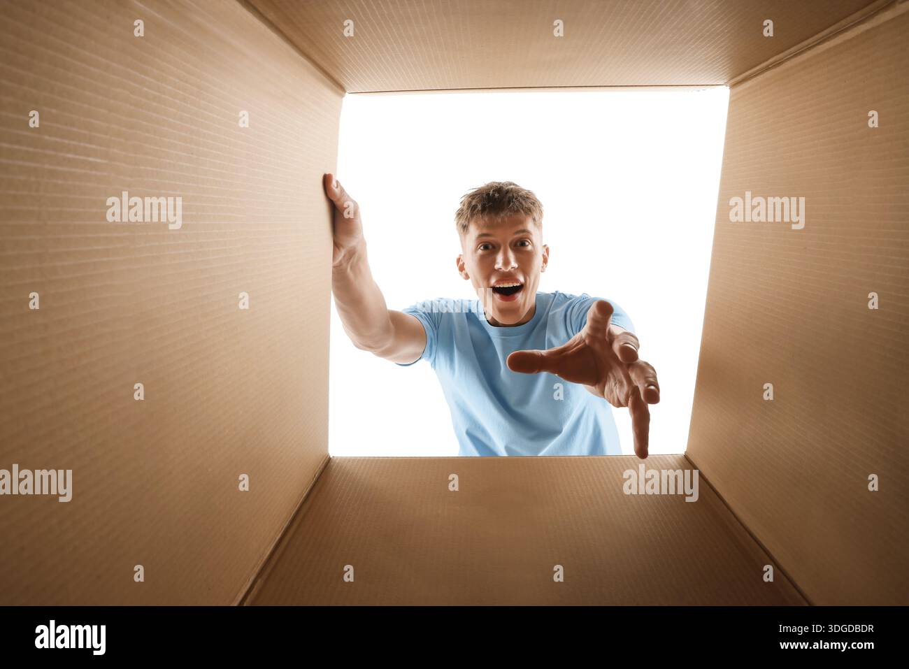 Man looking into cardboard box against white background, view from inside package Stock Photo