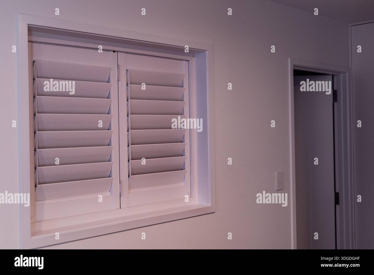 Closed White Shuttered Window Beside Interior Door Stock Photo