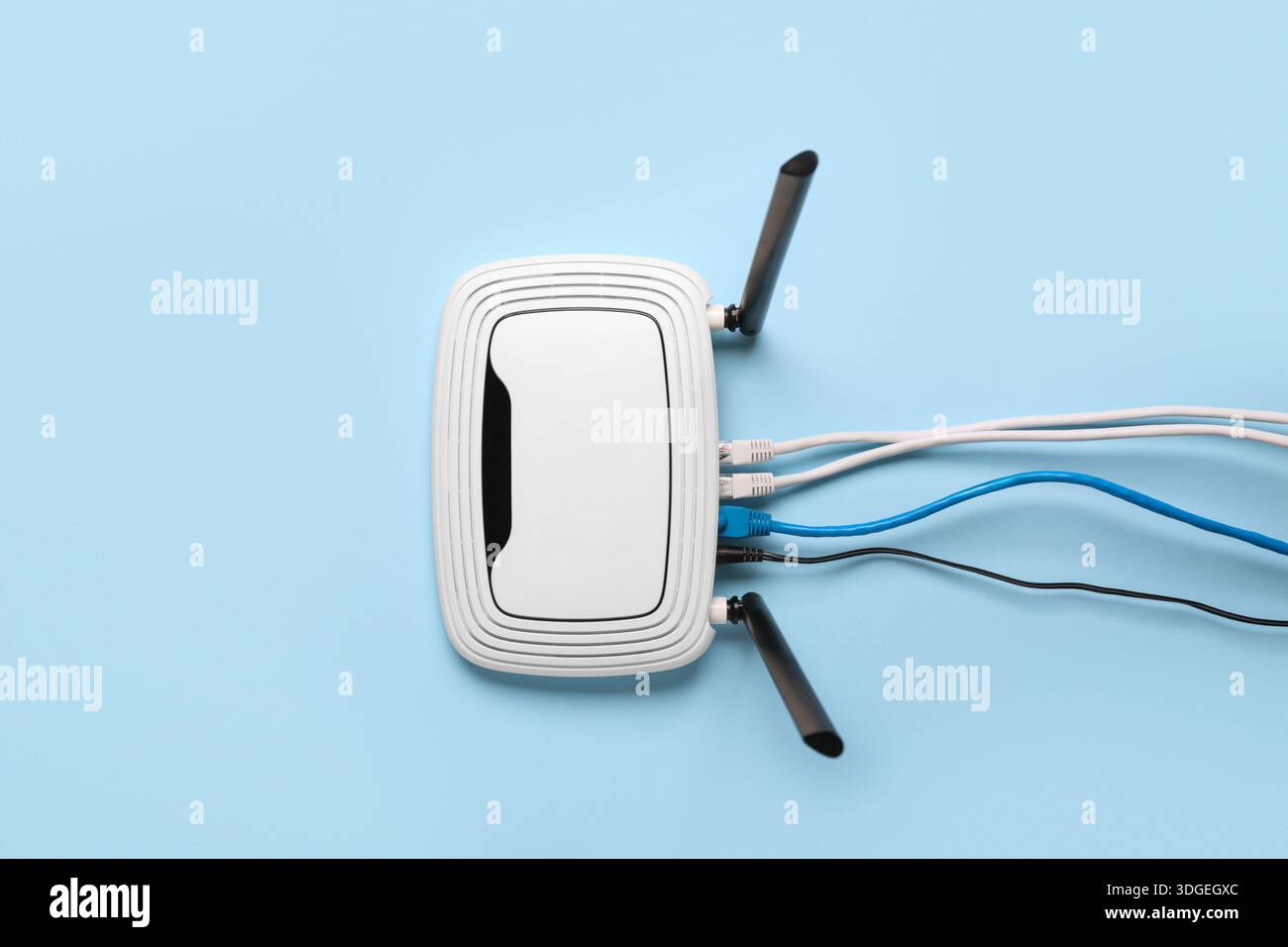 Modern wi-fi router with cables on blue background Stock Photo