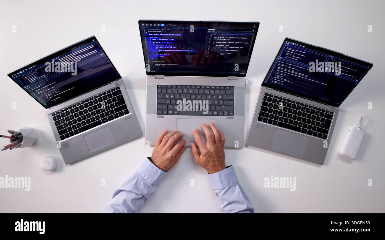 Skilled Programmer Creating Web Software On Multiple Laptops At Office. Stock Photo