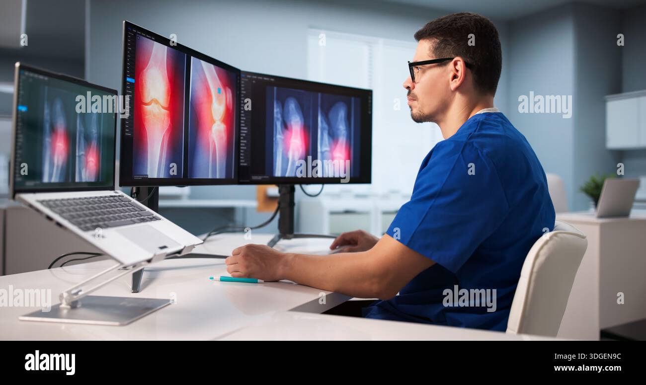 Young Latino Surgeon Examining Knee X-ray Using Advanced Software Technology. Stock Photo