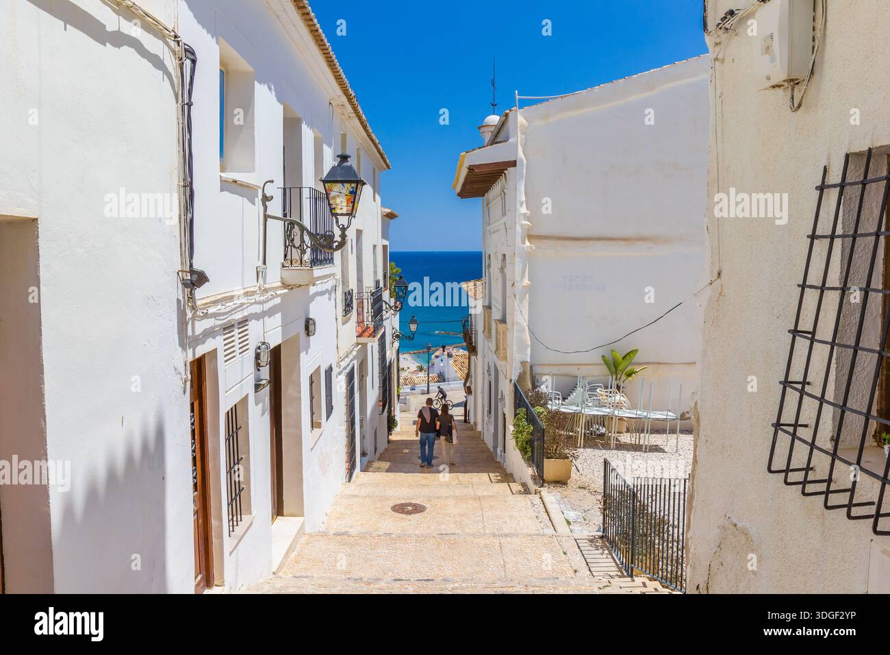 Couple walking towards the sea in a narrow street of Altea, Spain Stock Photo