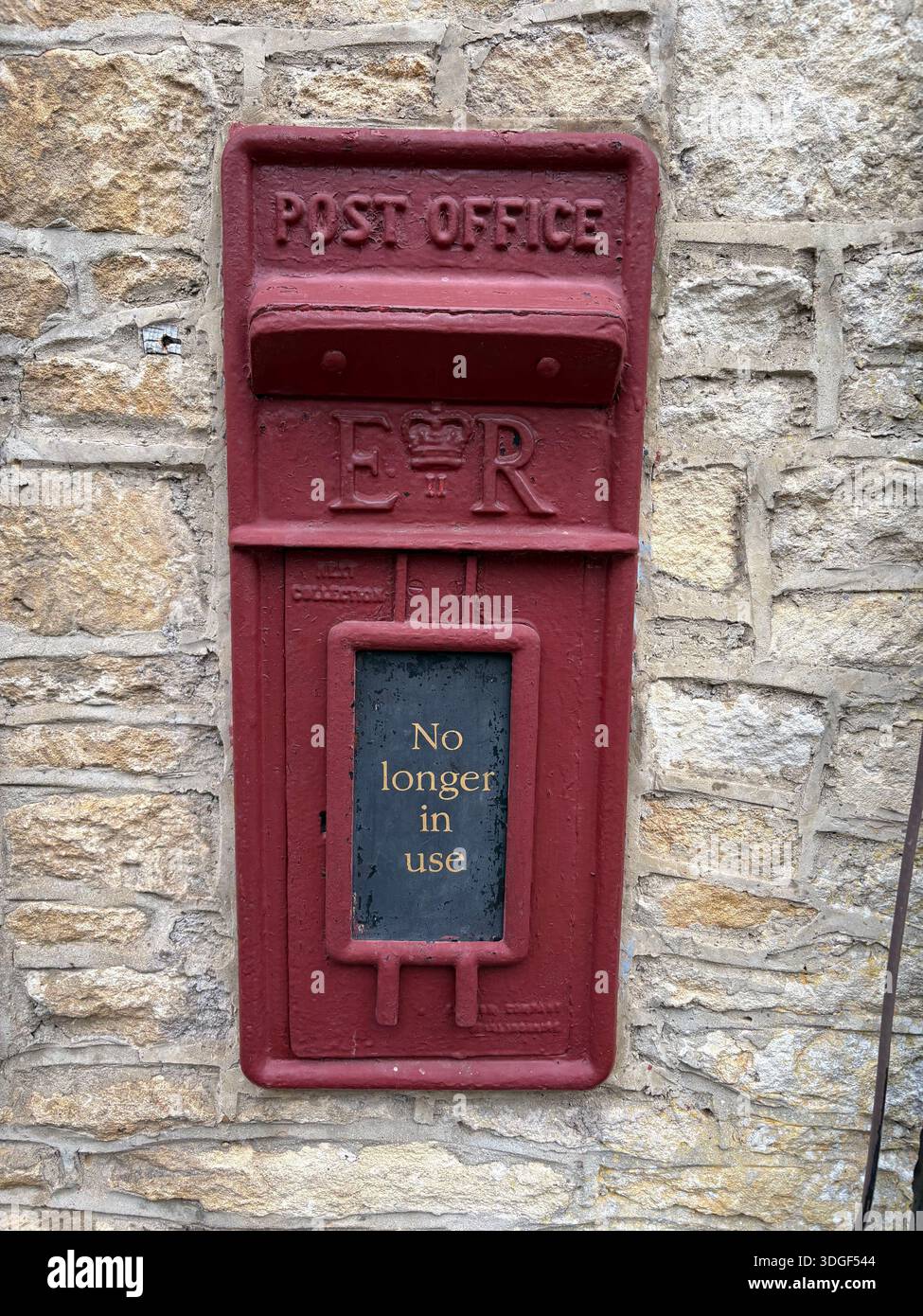 Old red British post box set into a stone wall, marked “No longer in use”, showing historic postal heritage in England. - Smartphone Captured Stock Image