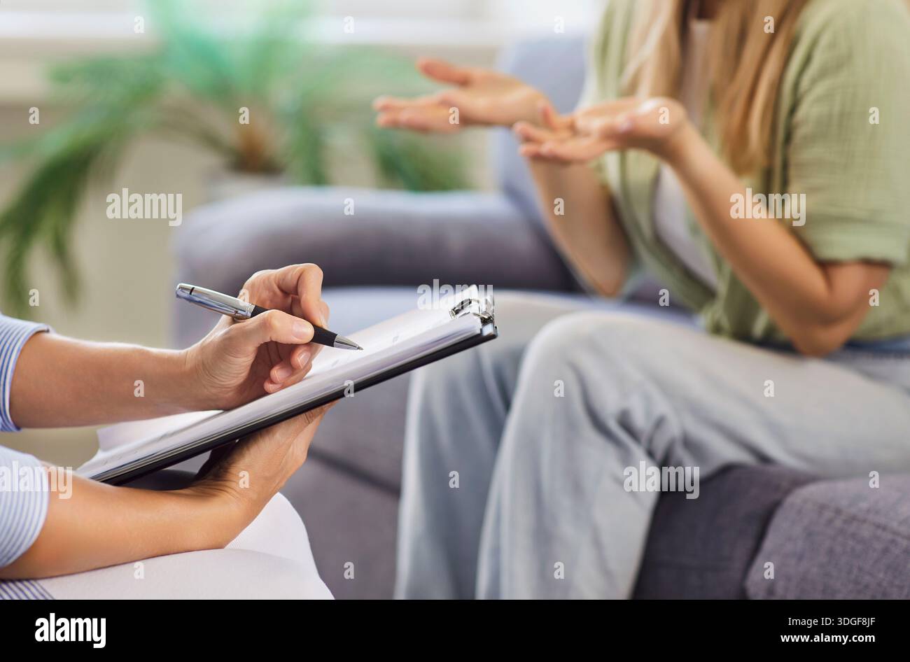 Therapist taking notes while patient gestures during supportive counseling session Stock Photo