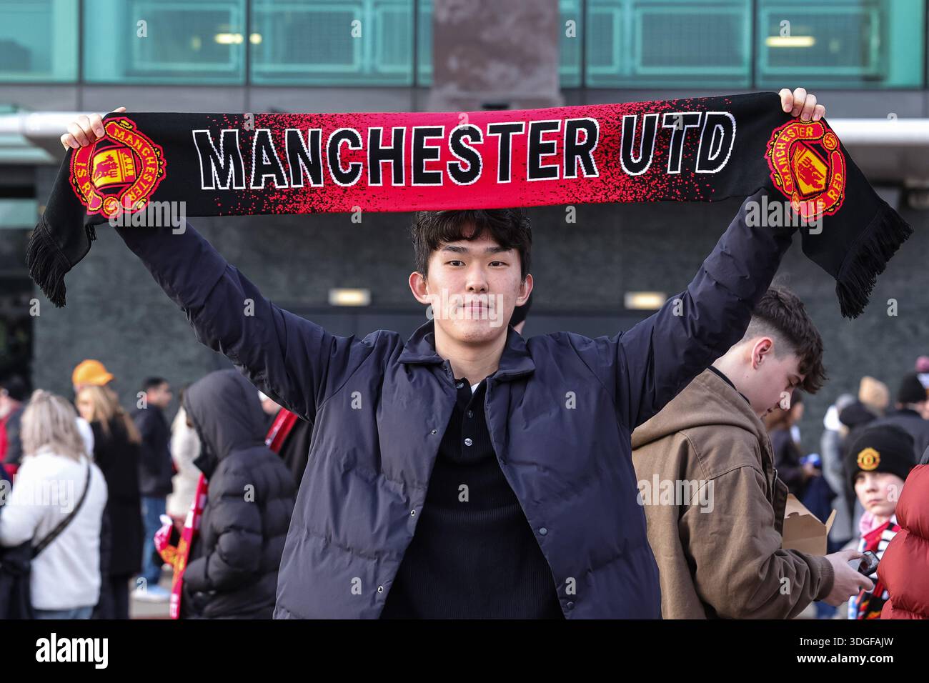 A Manchester United fan holds a UTD scarf above his head during the ...