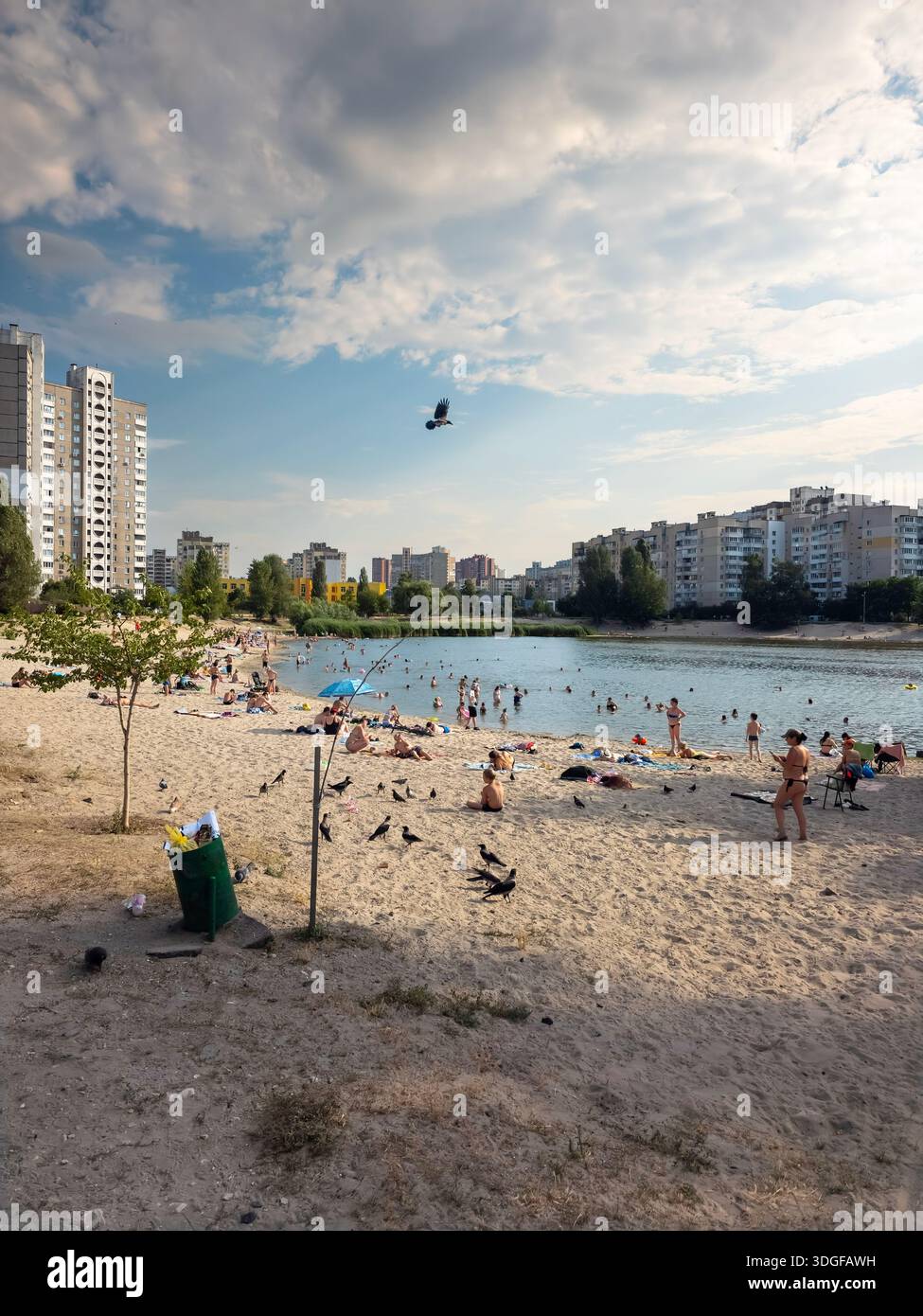 Kyiv, Ukraine - July 14, 2025: At sandy beach on Sonyachne Lake  people relaxing and swimming at hot july afternoon. A high rise residential buildings - Smartphone Captured Stock Image