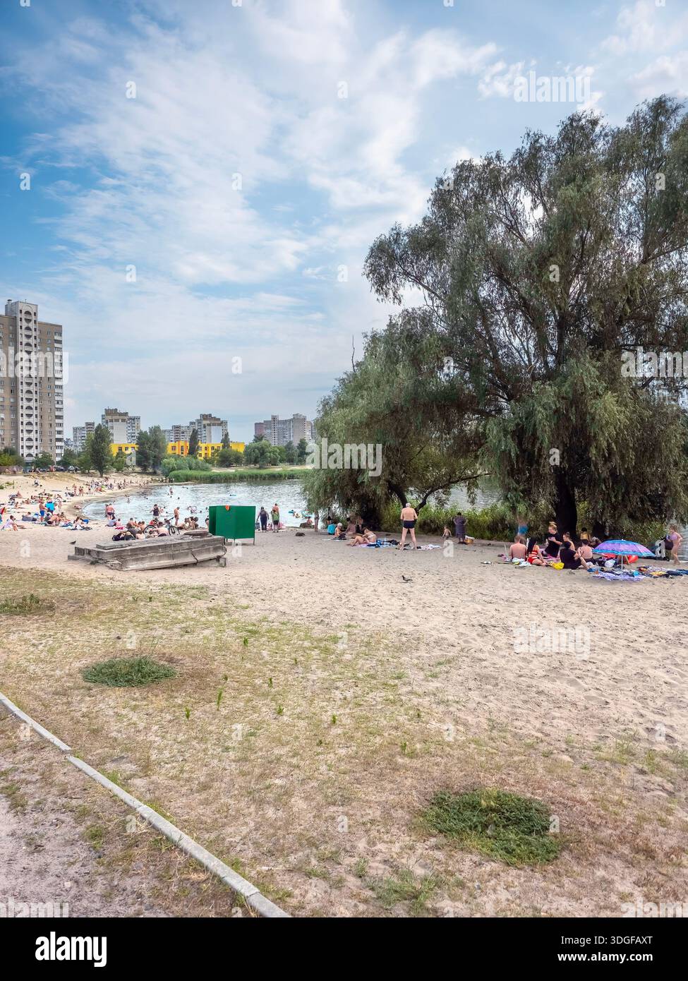 Kyiv, Ukraine - July 09, 2025: A sandy beach on Sonyachne Lake with people relaxing and swimming at hot july afternoon. A high rise residential buildi - Smartphone Captured Stock Image