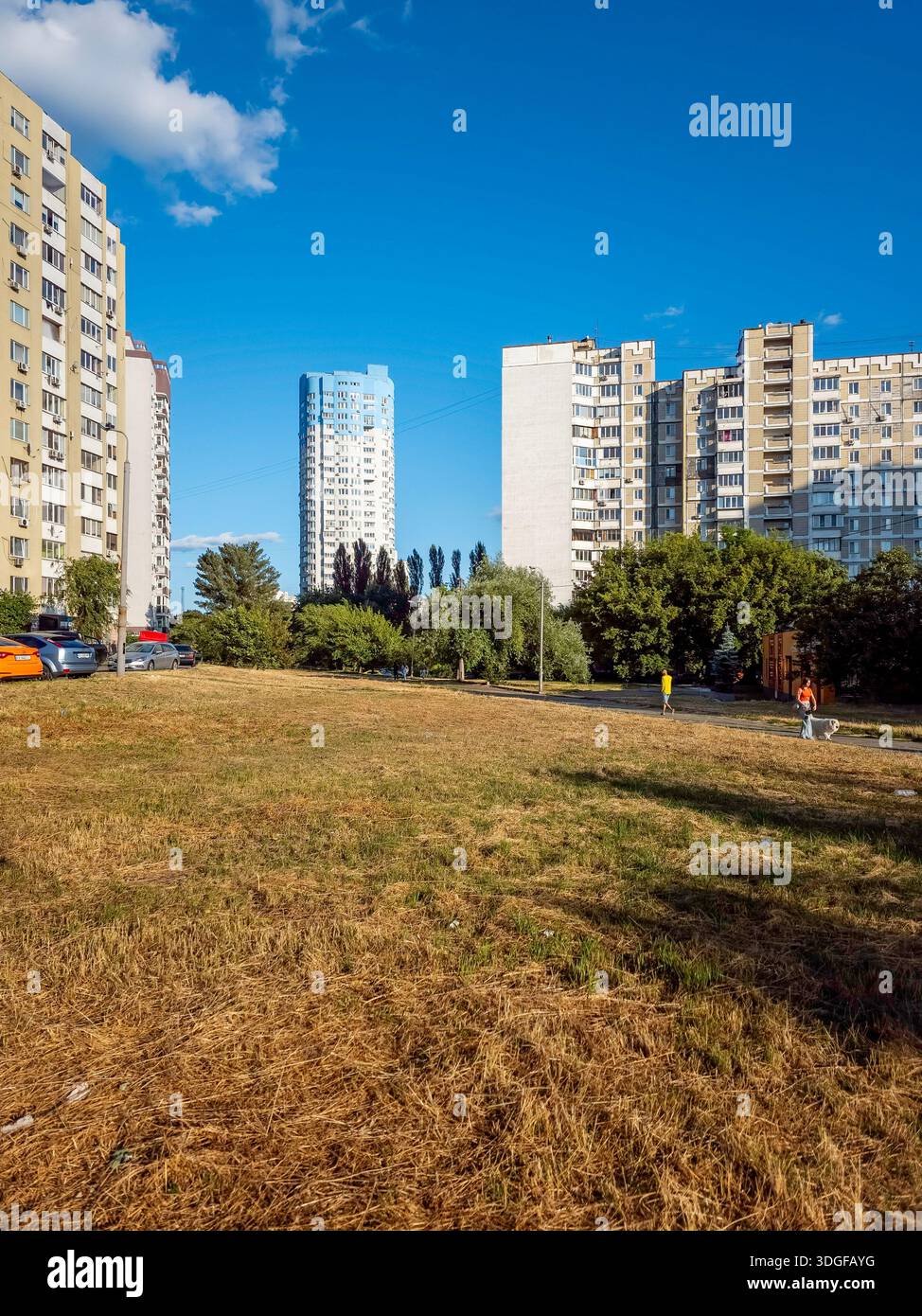 Kyiv, Ukraine - Jun 27, 2025: A high-rise residential building towers over the landscape from Kravchuka Street, with a large dry grass field in the fo - Smartphone Captured Stock Image