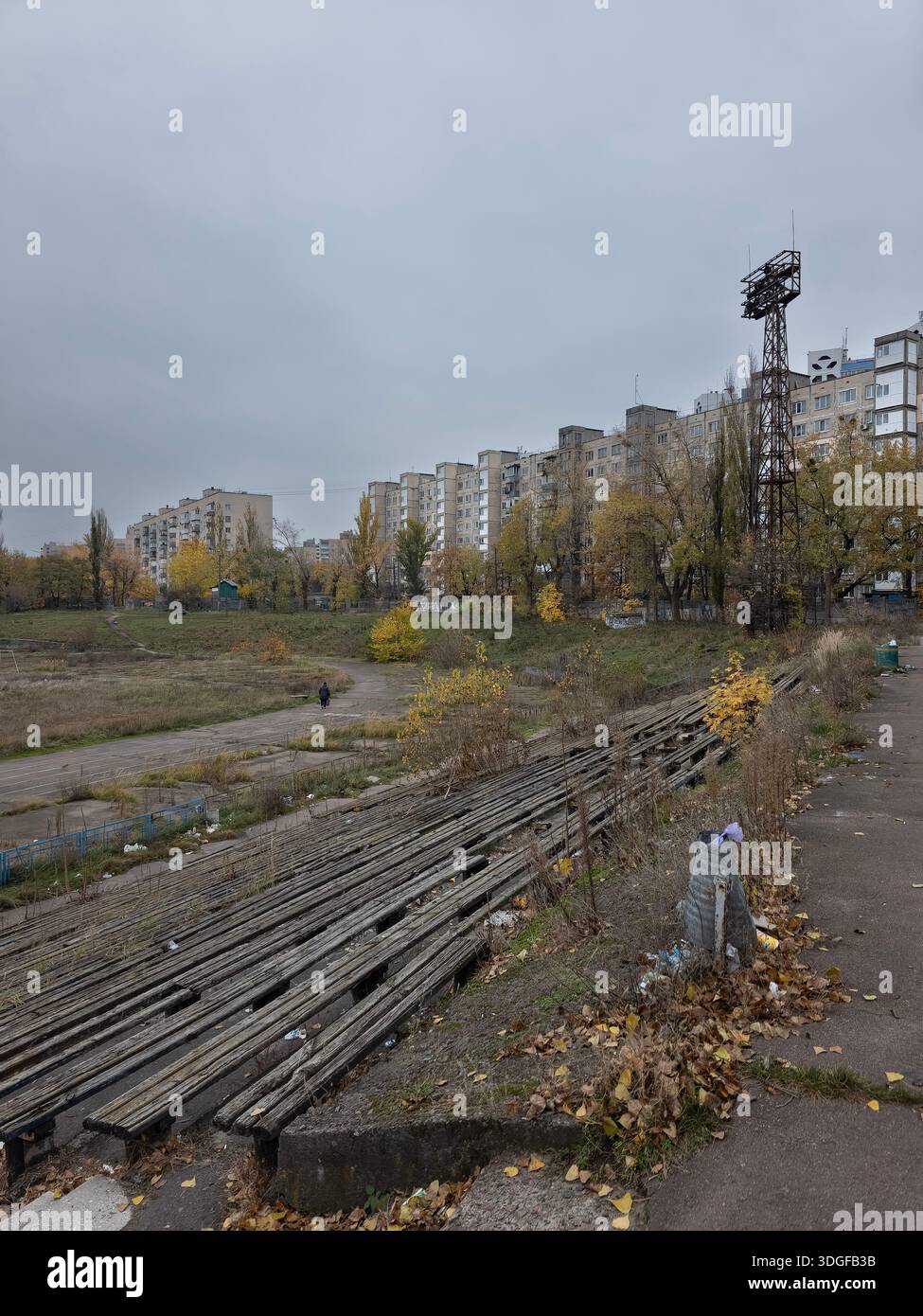 Old ruined stadium with rotten wooden benches and tall lighting mast. Darnytskyi district, Kyiv, Ukraine. Urban decay and sports arena abandonment. Gl - Smartphone Captured Stock Image