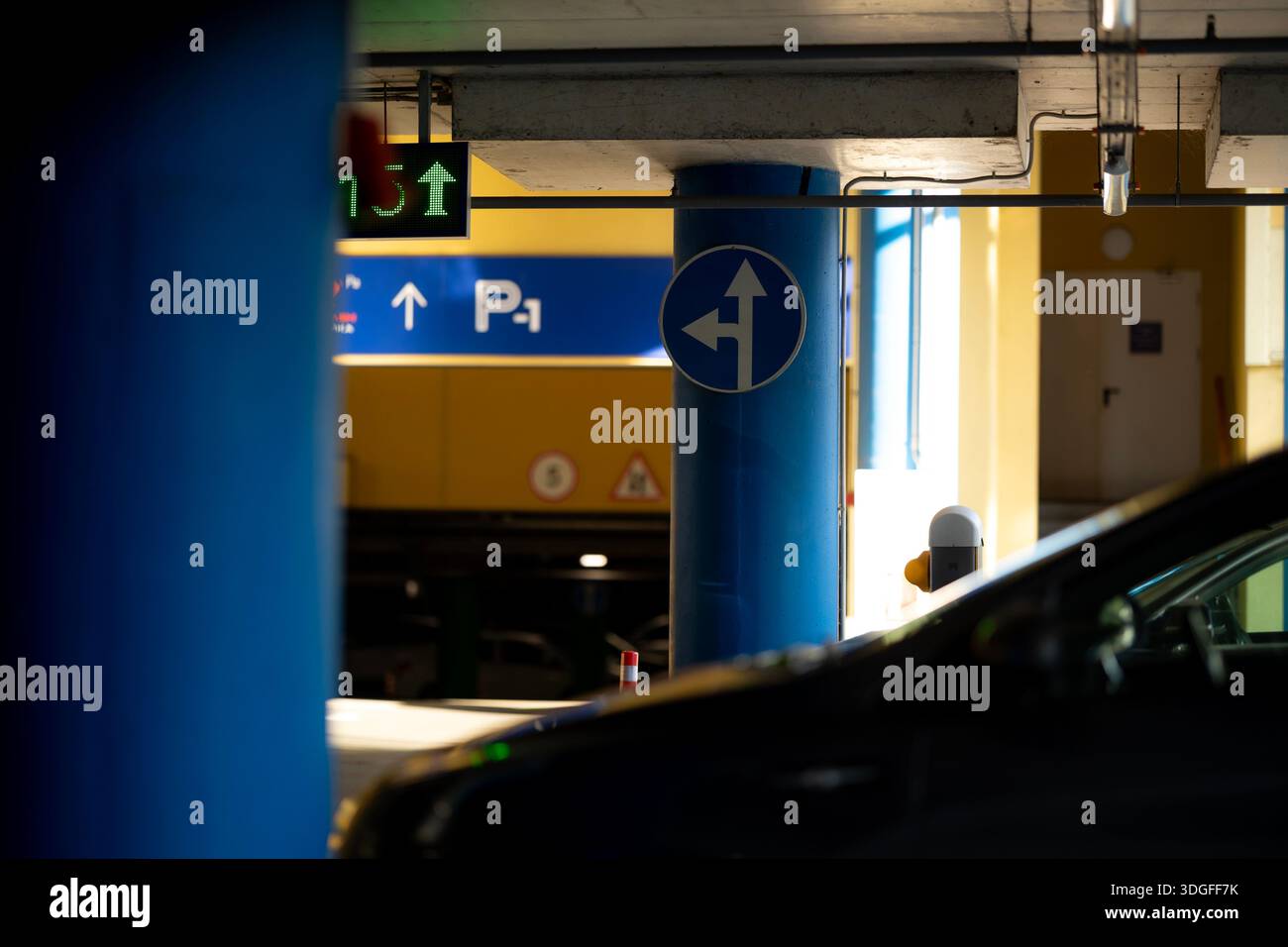 Interior view of a multi-level underground parking garage. Blue support columns, parked cars ...
