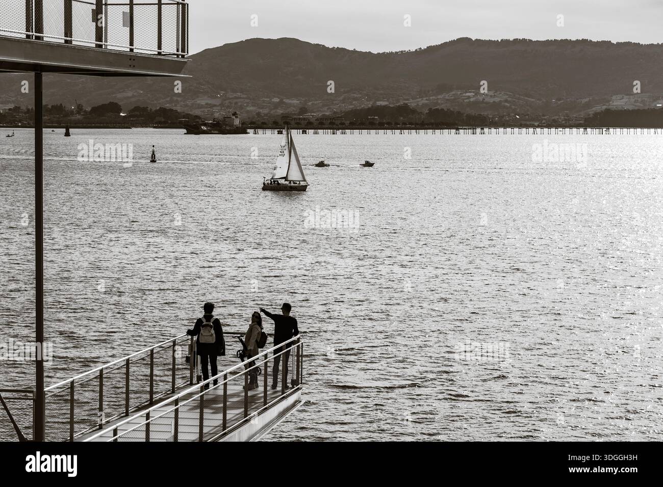 Santander, Spain – Nov 20, 2021: Black and white shot of a group of friends on the metal deck of Centro Botin with one person pointing at something in Stock Photo