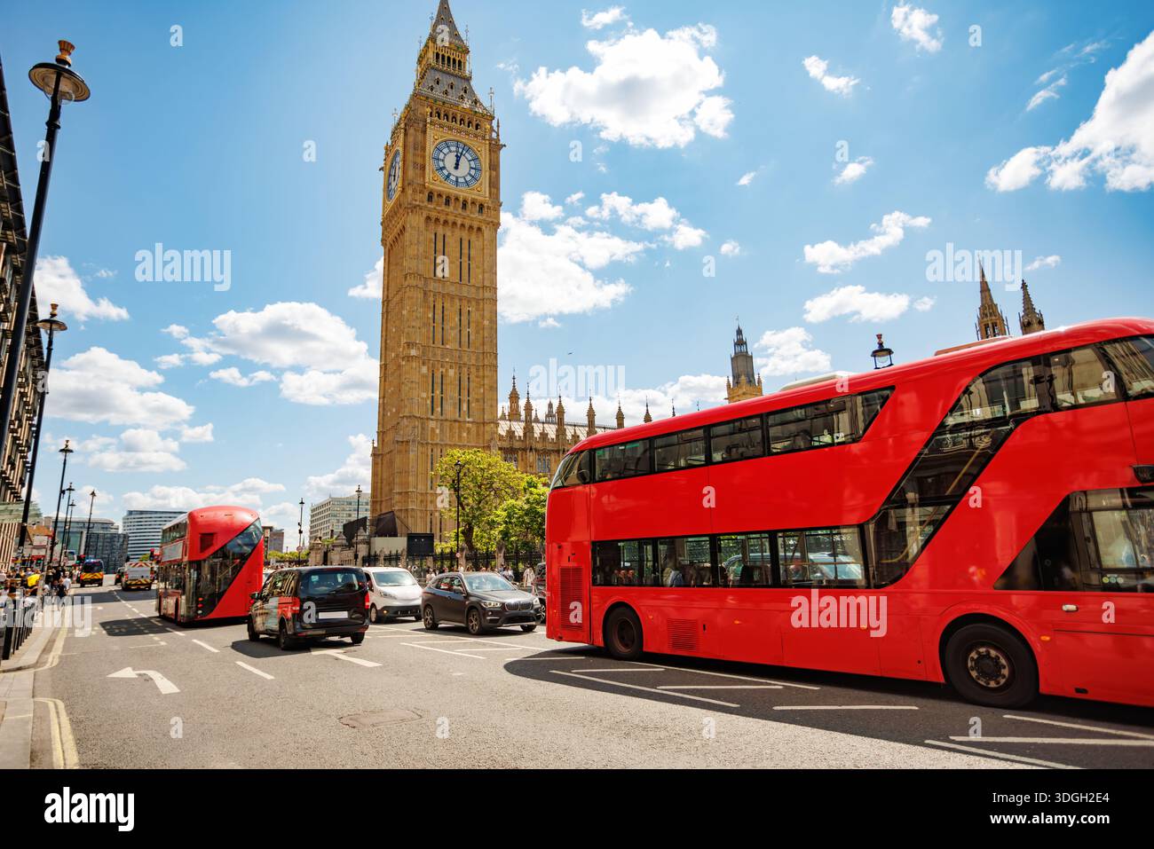Red double-decker buses traveling past Big Ben in London, UK Stock