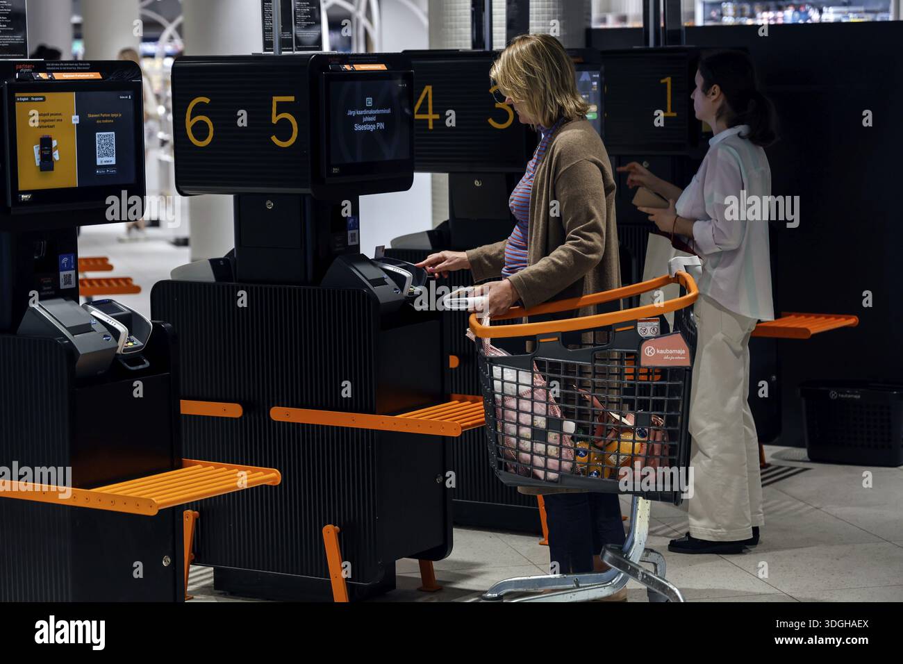 Customers use self-service checkouts with shopping trolleys in the ...