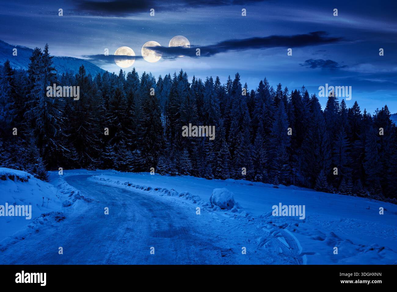 winter landscape with snow covered country road winding through fir forest in mountains at night. alpine countryside of in full moon light. inner stre Stock Photo