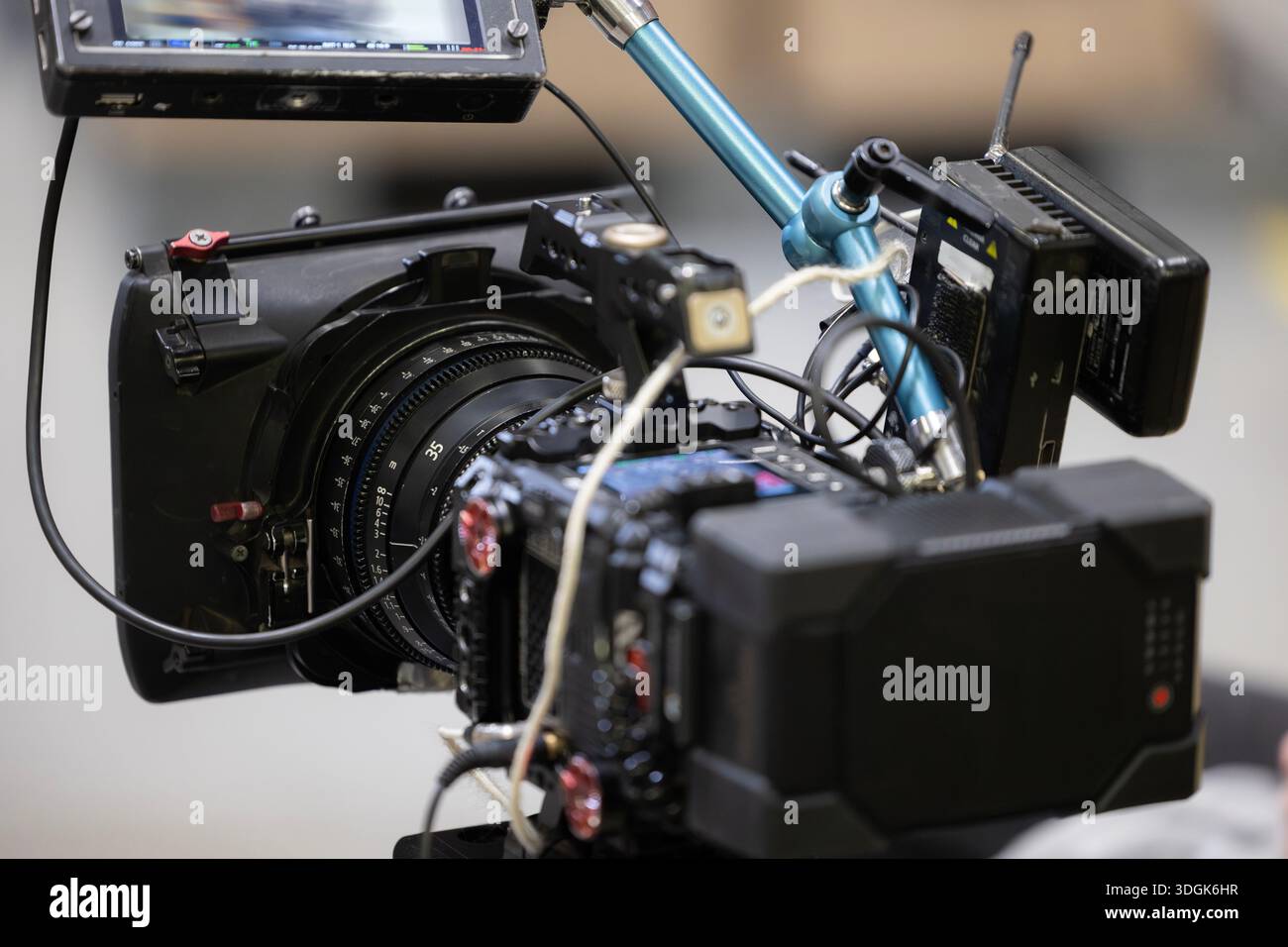 A professional digital cinema camera rig with a compact prime 35mm lens, a large v-mount battery. This behind-the-scenes view shows the matte box, mon Stock Photo