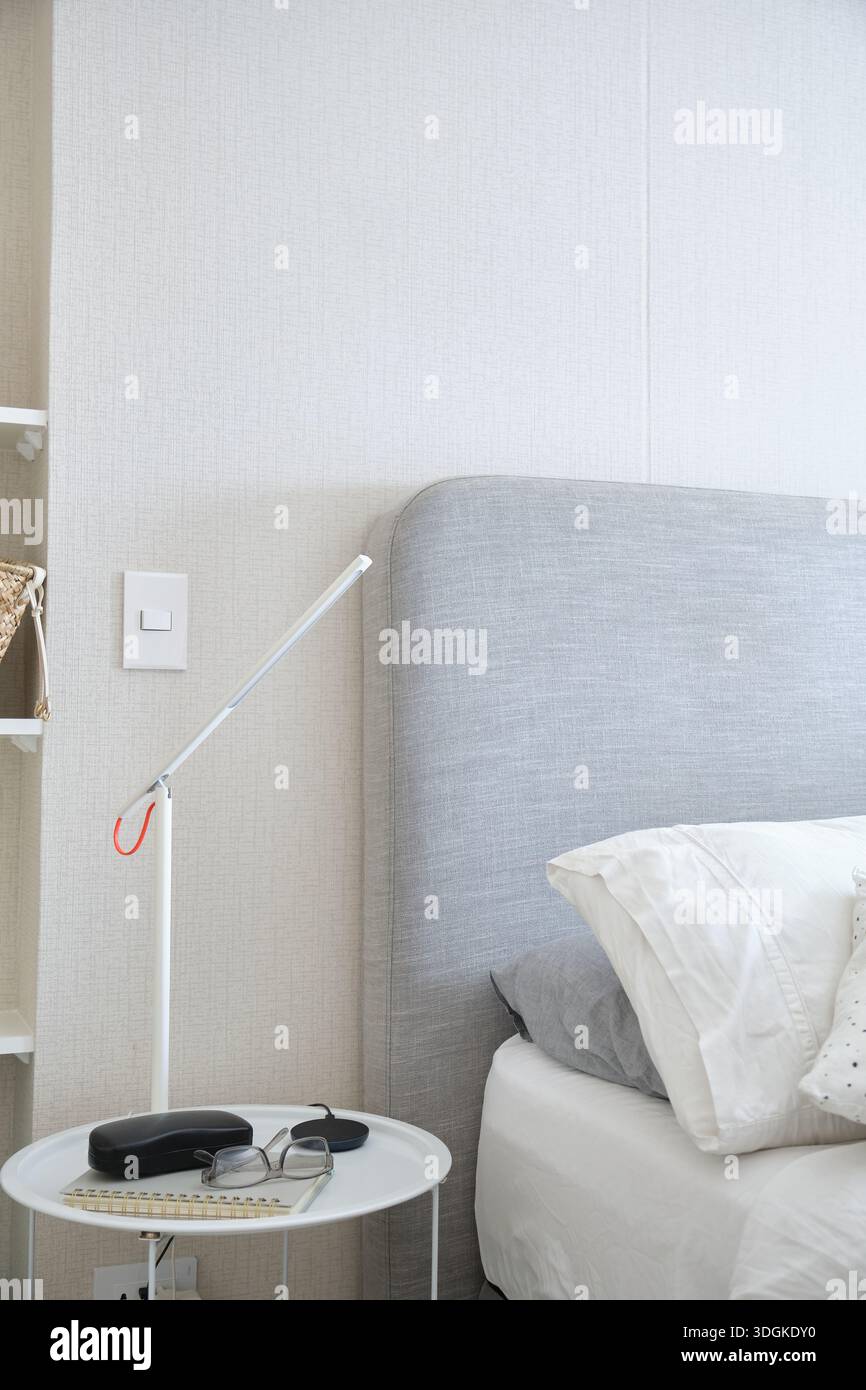 Bedroom interior showcasing minimal design with a functional light source and reading accessories Stock Photo