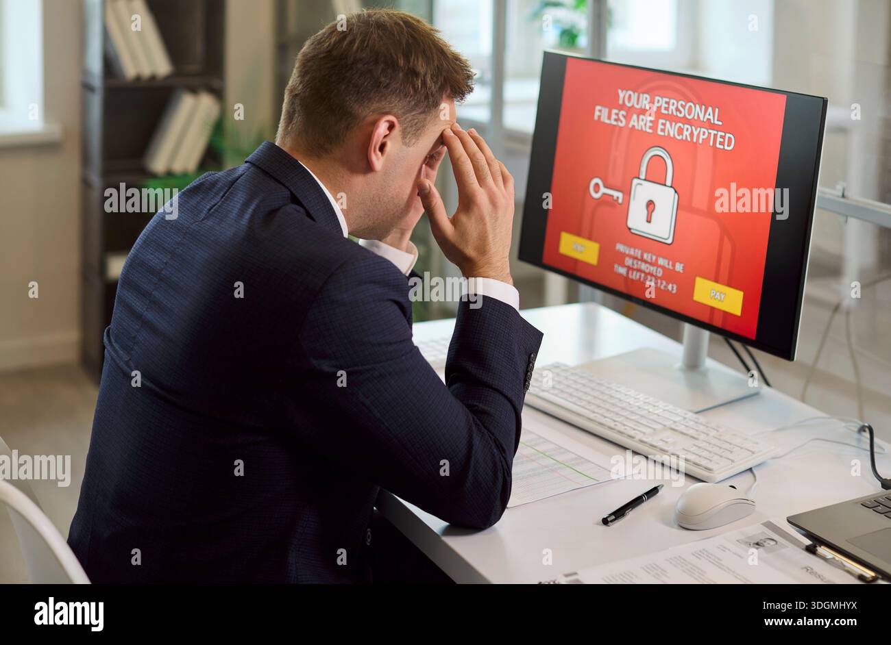 Stressed businessman facing ransomware on office computer with encrypted files Stock Photo
