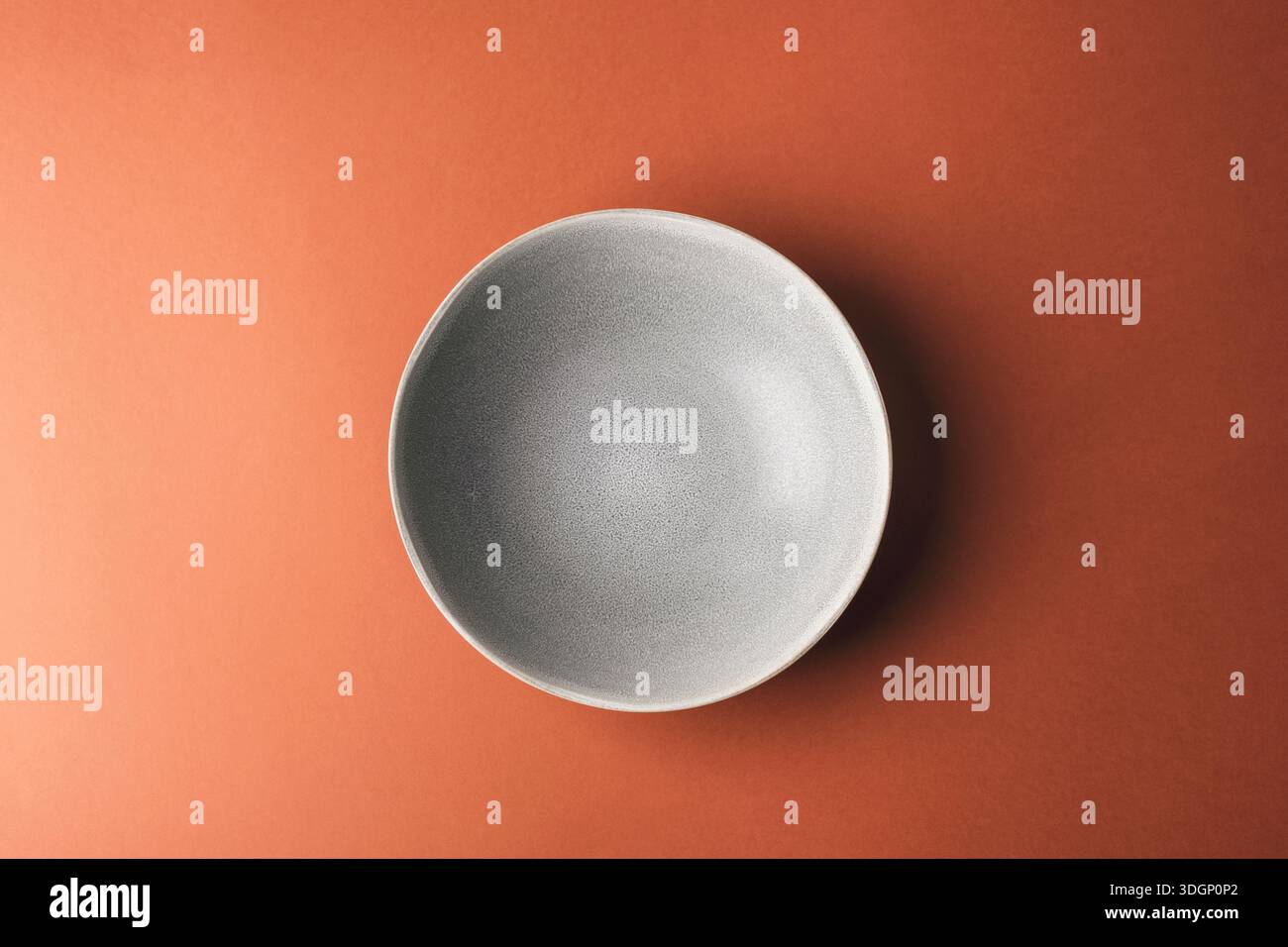 Grey plate on warm brown background. Top view, flat lay. Stock Photo