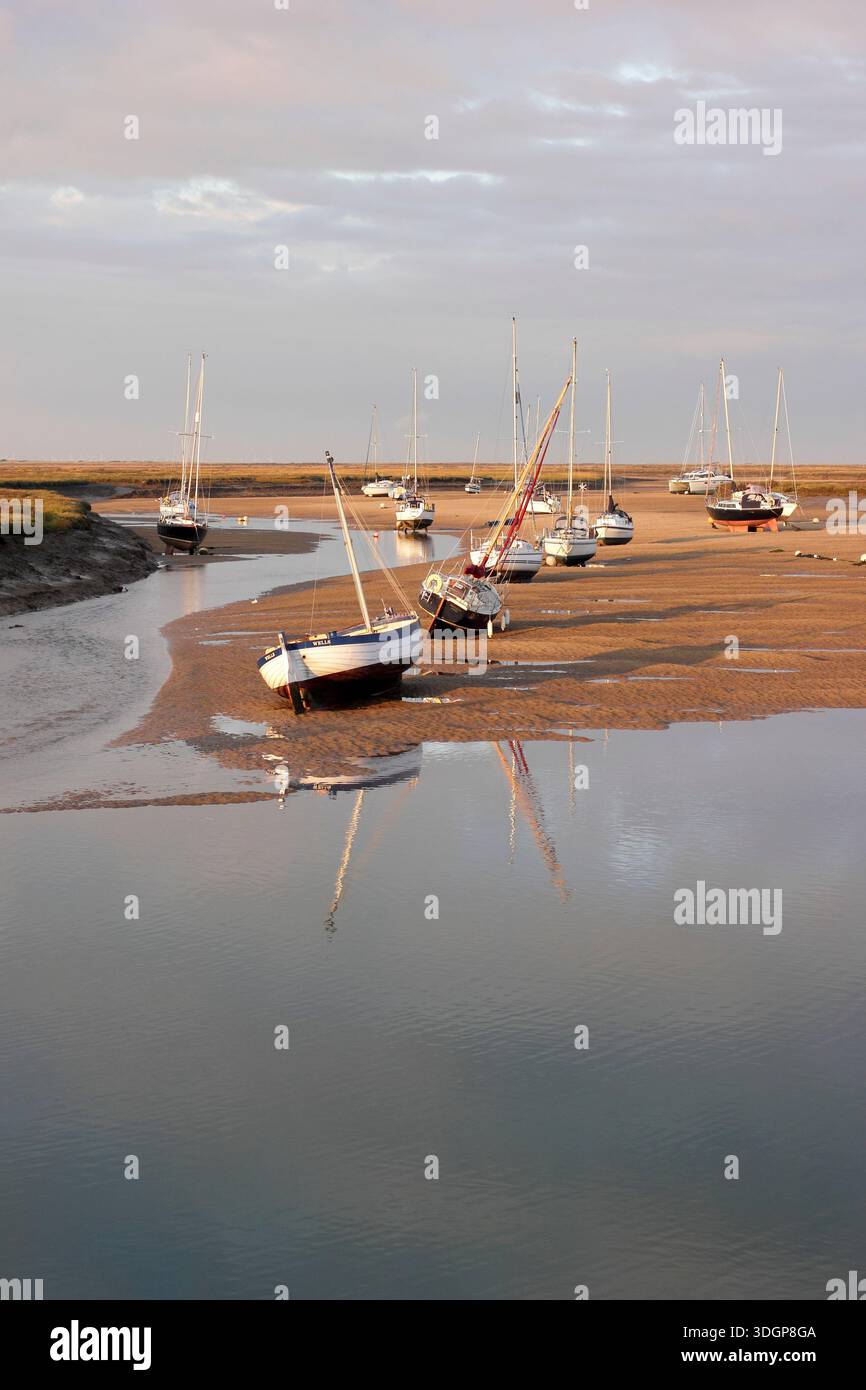 Wells next the Sea. Boats at low tide in the sand channel creek at Wells next the Sea harbour, looking to saltmarshes. North Norfolk, England, Britain Stock Photo