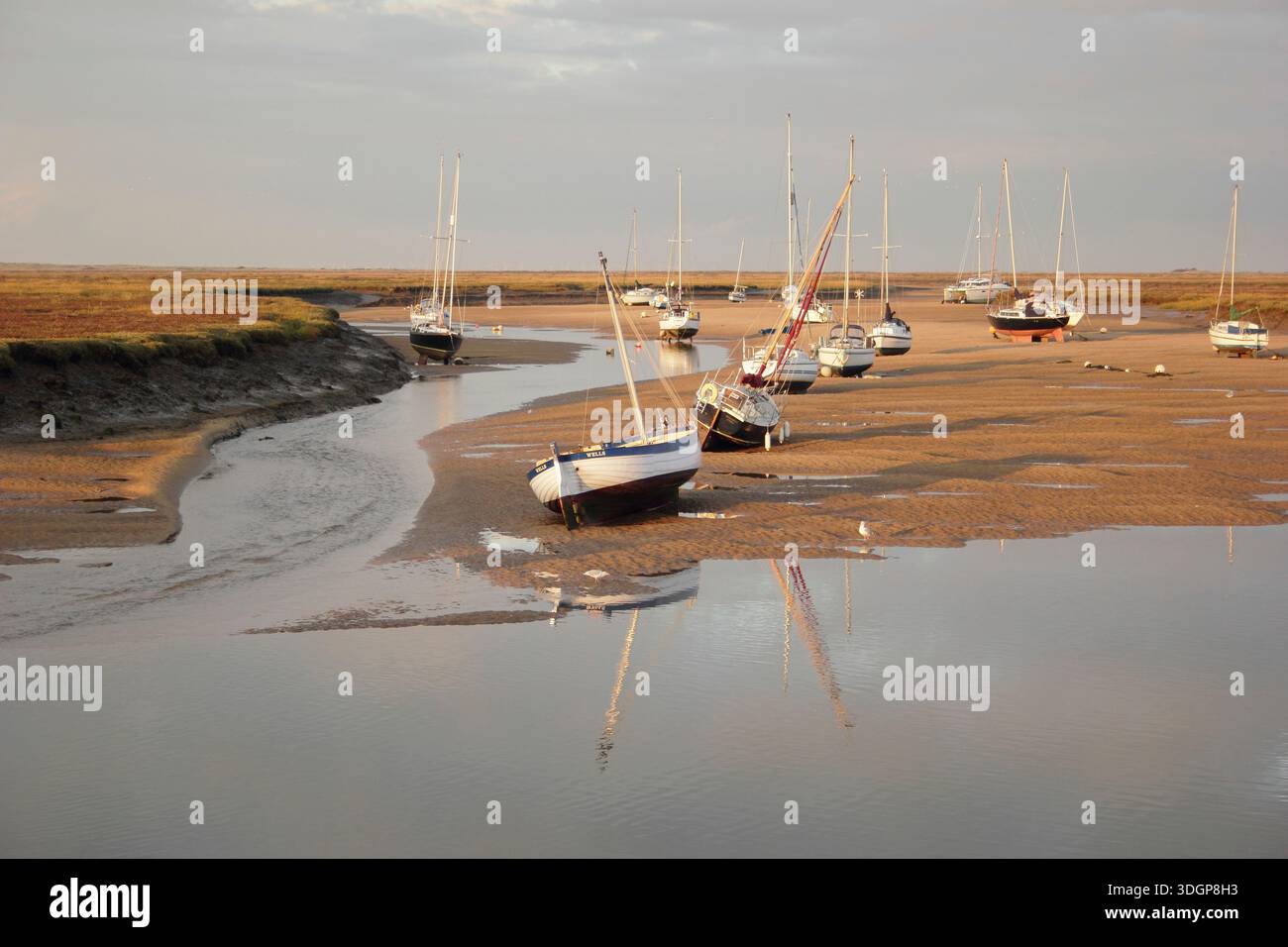 Wells next the Sea. Boats at low tide in the sand channel creek at Wells next the Sea harbour, looking to saltmarshes. North Norfolk, England, Britain Stock Photo