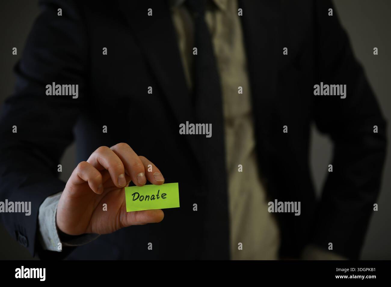 Businessman shows a wooden block with the word donate. Charitable donation in business concept. Stock Photo