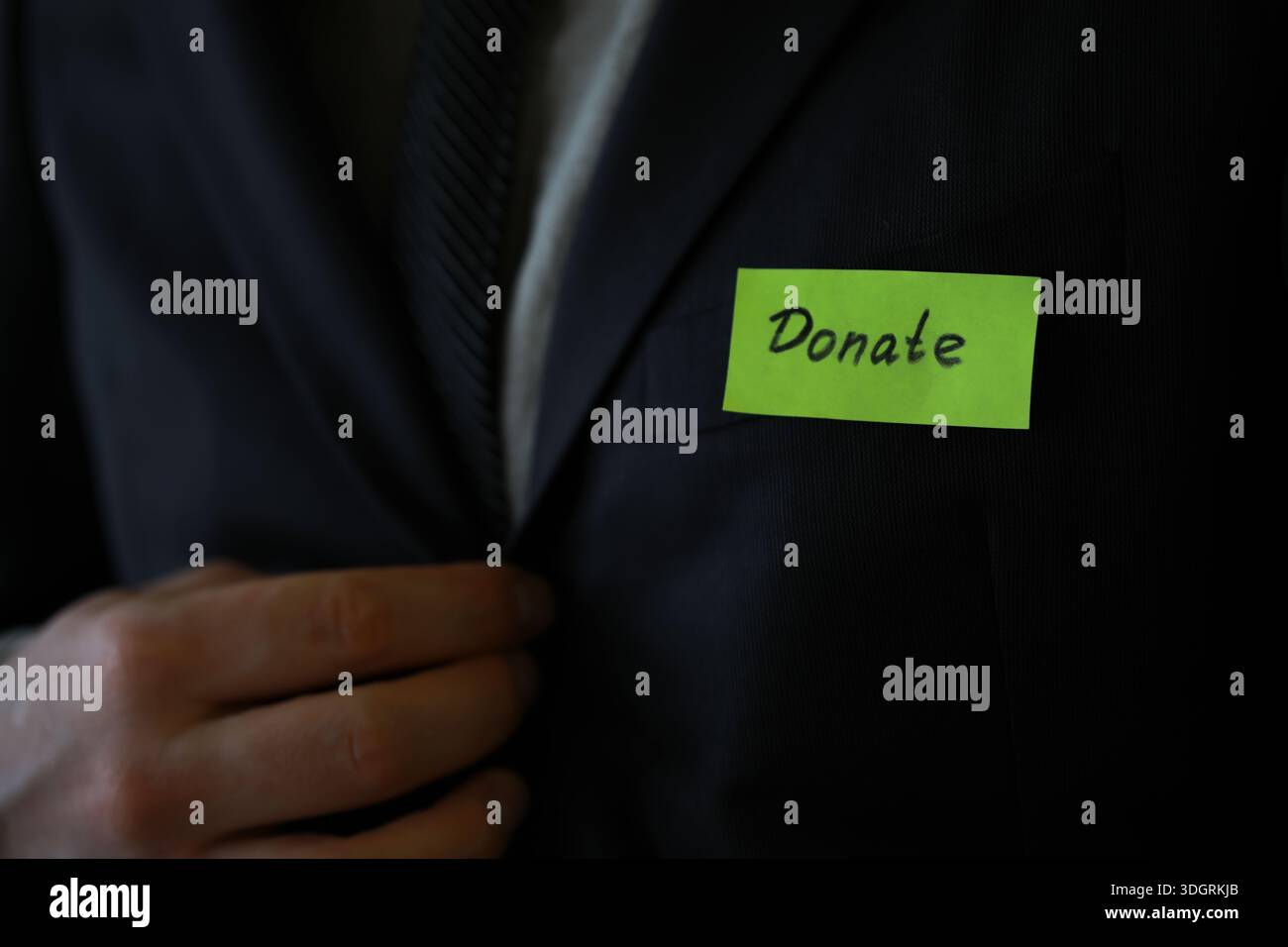 Businessman shows a wooden block with the word donate. Charitable donation in business concept. Stock Photo