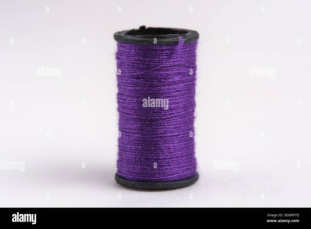 Spool purple thread on white background, closeup Stock Photo