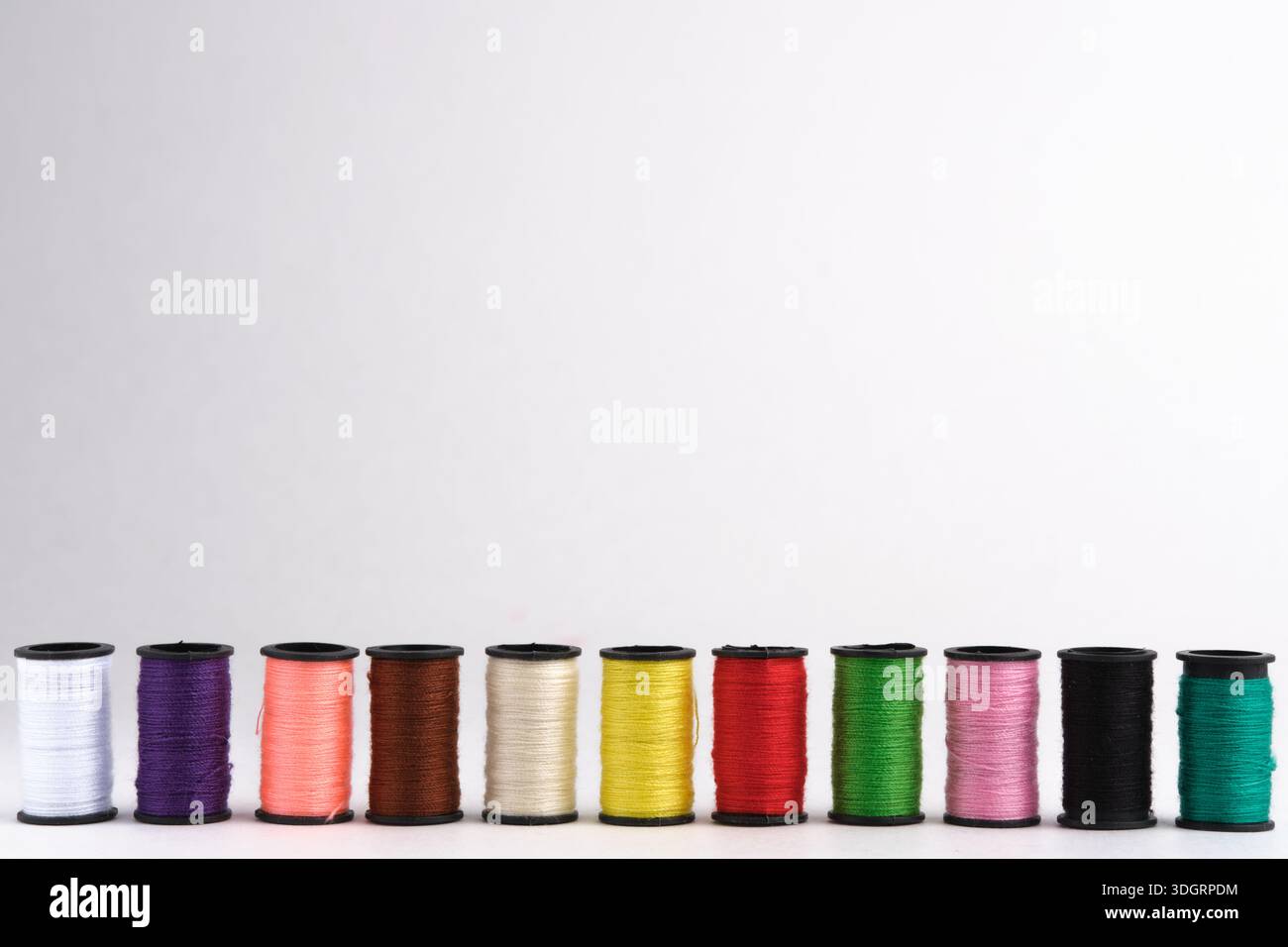 Spools of multicolored sewing threads on white background Stock Photo