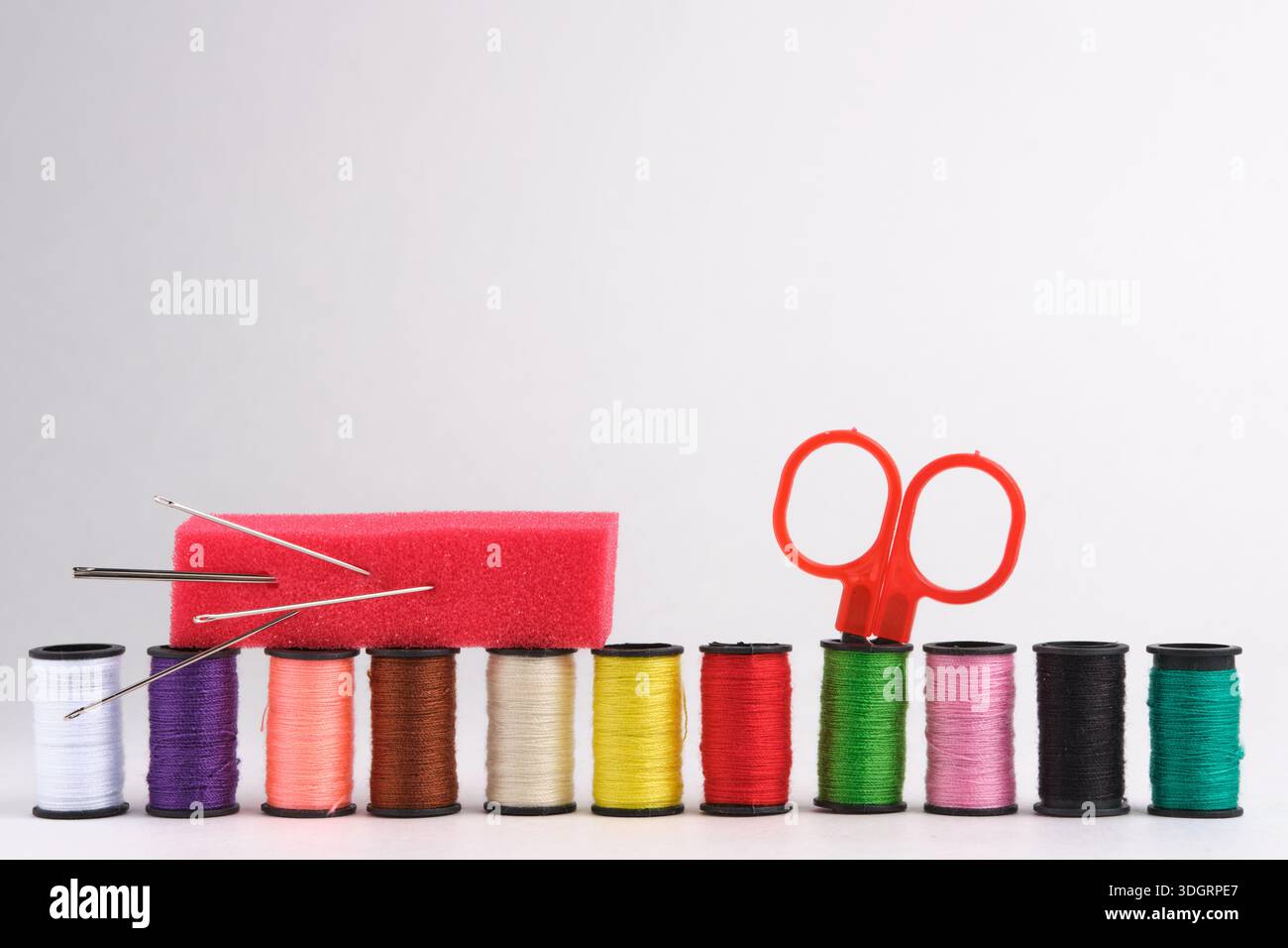 Spools of thread, scissors and needle on white background Stock Photo