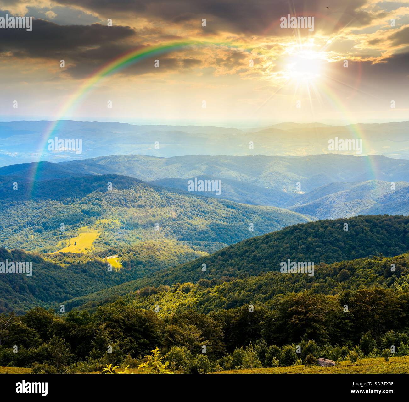 mountain landscape with rolling hills at sunset. summer countryside scenery with view in to distant valley and green forested slopes in evening light. Stock Photo