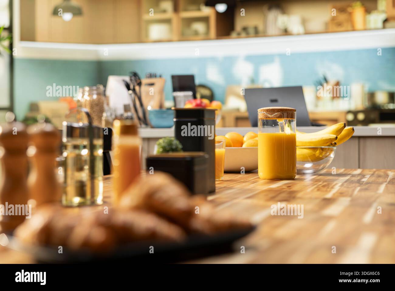 Bright modern kitchen interior with elegant furniture and wooden cupboards. Cookware and fresh vegetables on a cutting board, showcasing a stylish household and luxury home design. Stock Photo