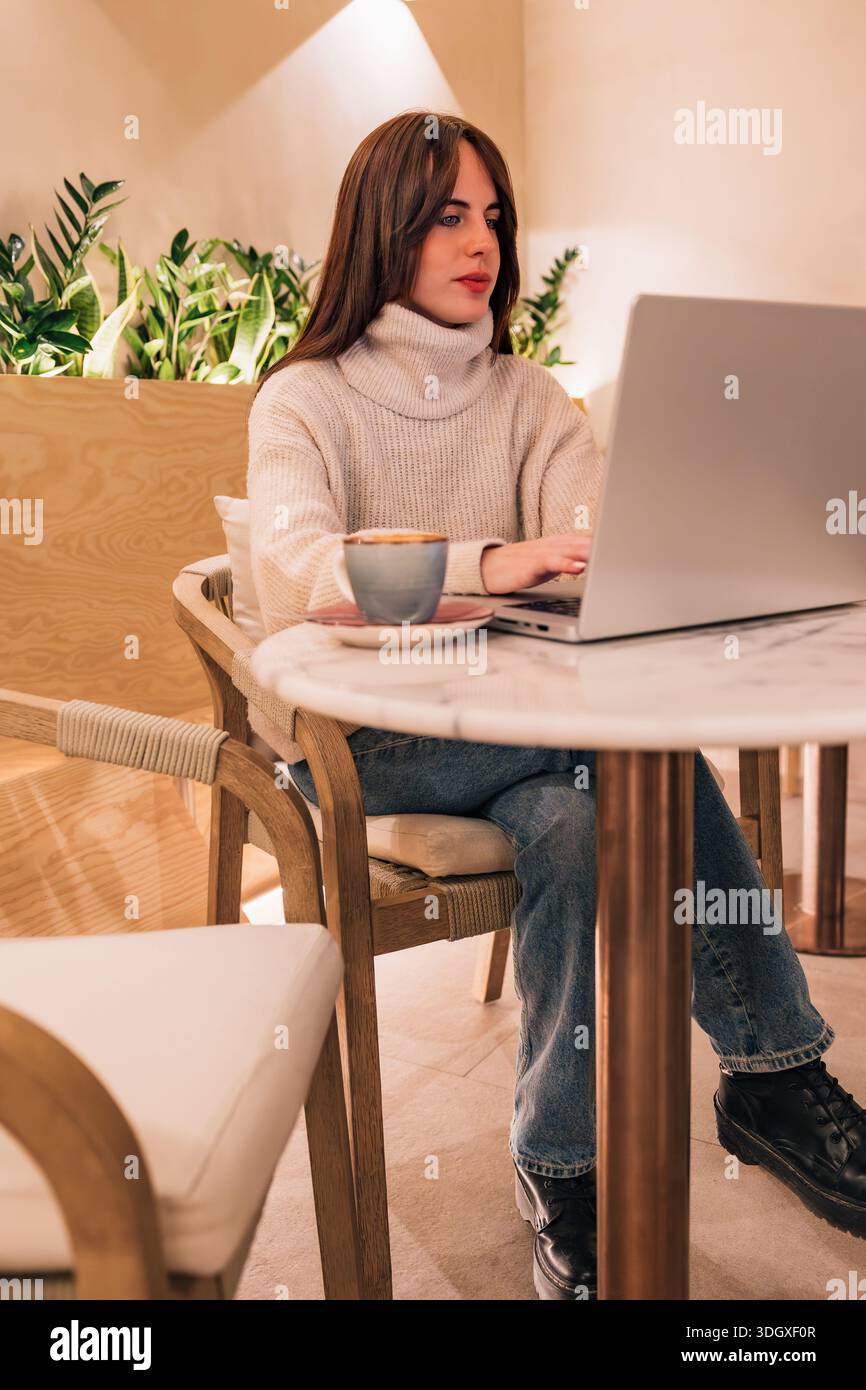 Woman remote working using laptop in cafe Stock Photo