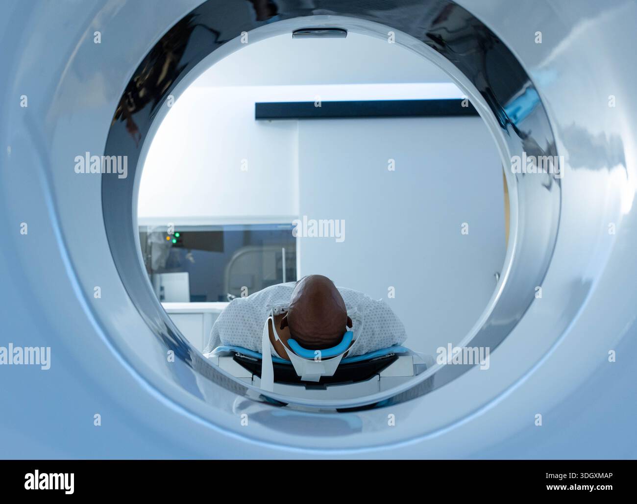 Scanner bore framing patient supine on motorized table in radiology room, showing blue head coil. Imaging, hospital, clinical, sterile, minimalist, ca Stock Photo