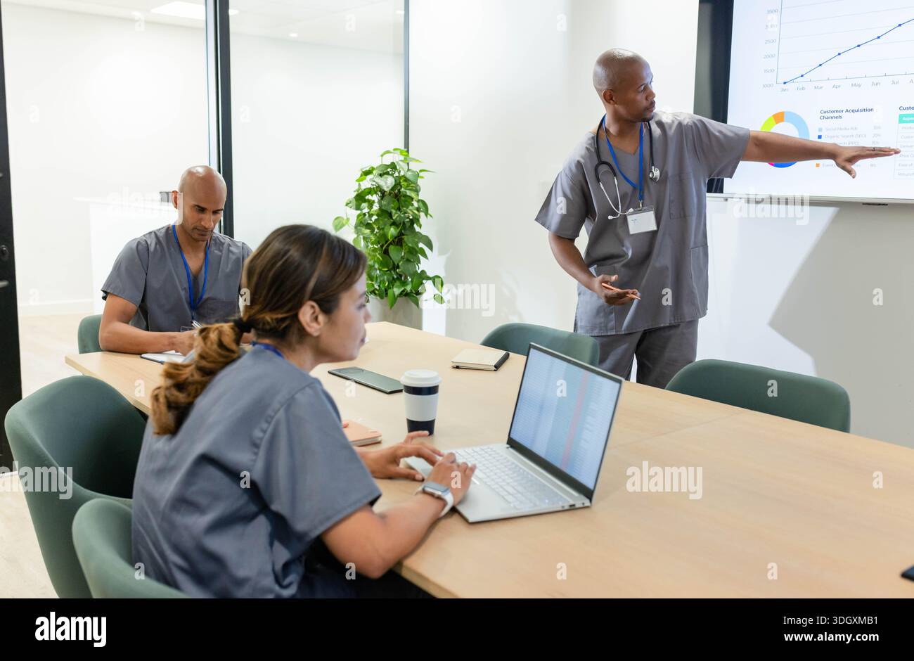 African American team meeting at clinic, standing male presenting, pointing at display, copy space. Dashboard, collaboration, healthcare, hospital, cl Stock Photo