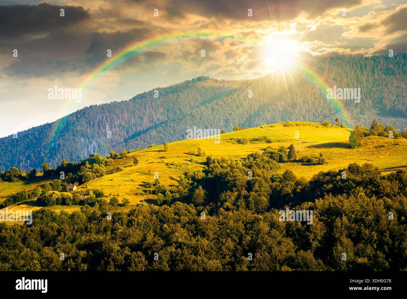 mountainous countryside landscape with rolling hills on summer sunset. rural area in evening light. beautiful view of place with green grassy pastures Stock Photo