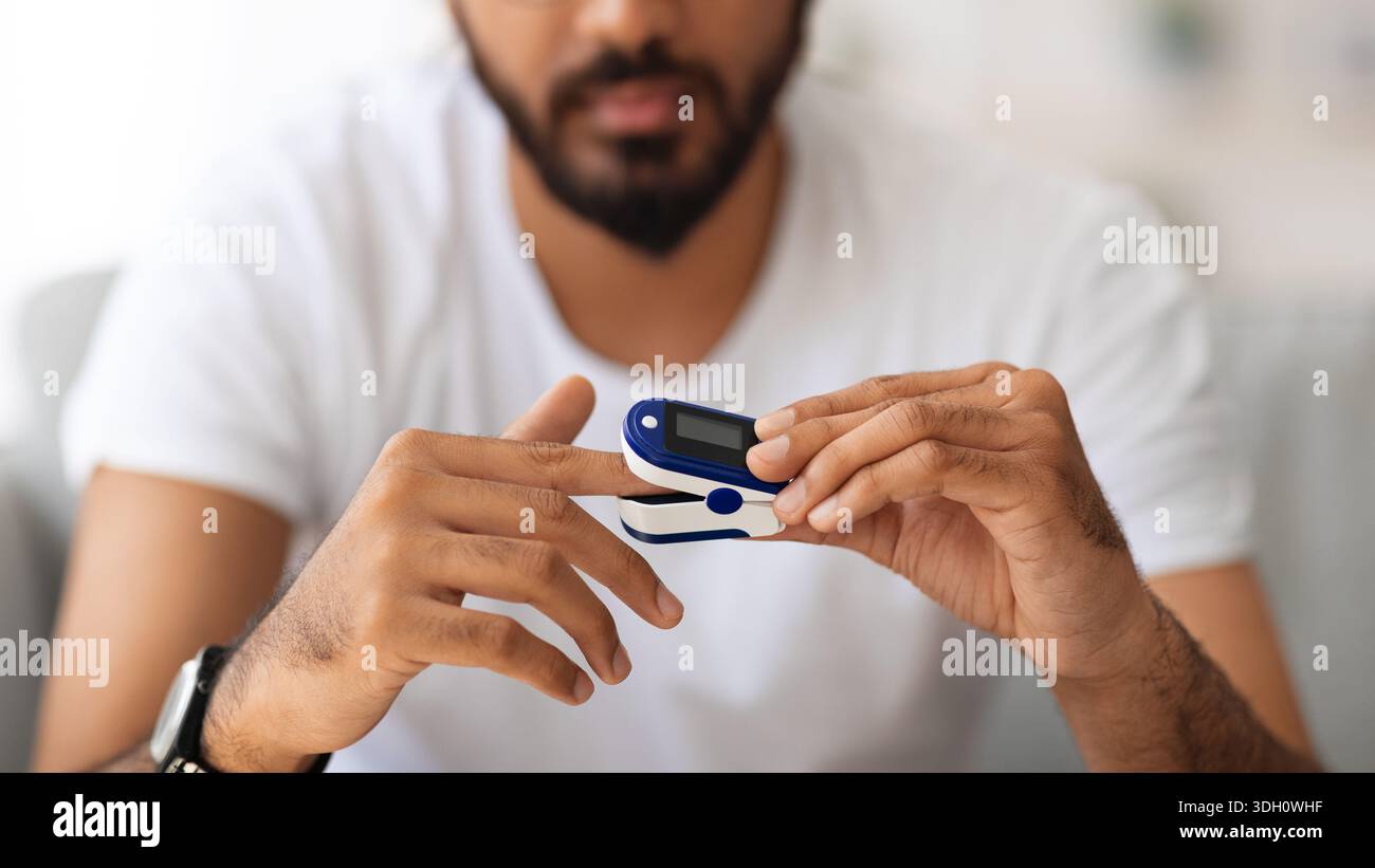 Unrecognizable man using pulse oximeter at home Stock Photo
