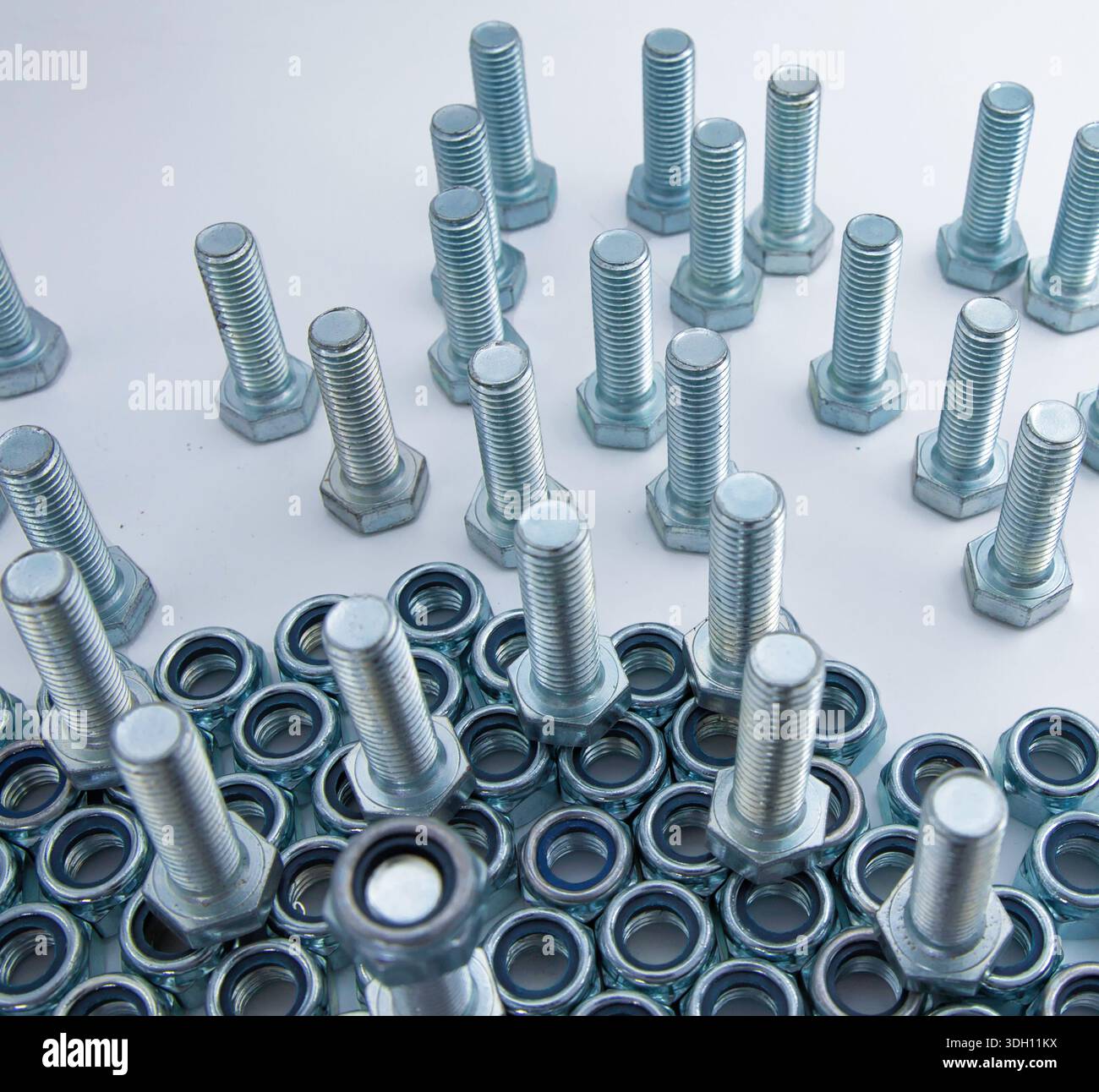 Metal bolts and hex nuts arranged on flat surface low angle view Stock Photo