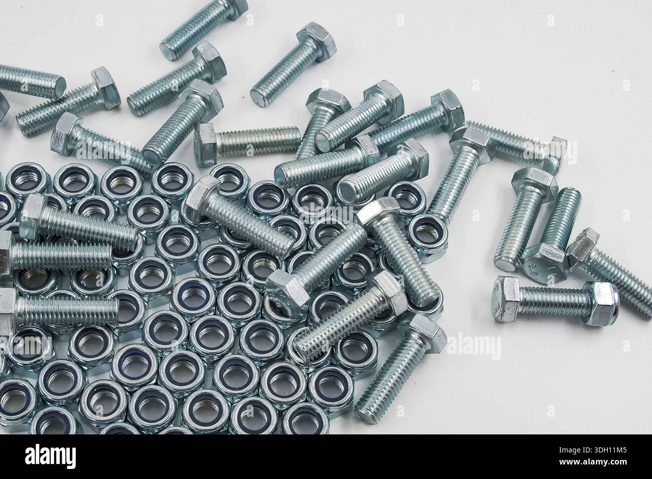 Metal bolts and hex nuts arranged on flat surface low angle view Stock Photo